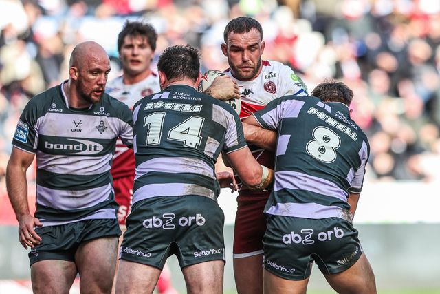 Kaide Ellis of Wigan Warriors is tackled by Fenton Rogers of Huddersfield Giants and Tristan Powell of Huddersfield Giants during the Betfred Super League round 6 match Wigan Warriors vs Huddersfield Giants at The Brick Community Stadium, Wigan, United Kingdom on 28 March 2026

(Photo by Alfie Cosgrove/News Images)