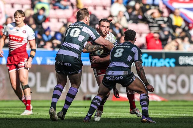 Kaide Ellis of Wigan Warriors is tackled by Tom Burgess of Huddersfield Giants and Tristan Powell of Huddersfield Giants during the Betfred Super League round 6 match Wigan Warriors vs Huddersfield Giants at The Brick Community Stadium, Wigan, United Kingdom on 28 March 2026

(Photo by Alfie Cosgrove/News Images)
