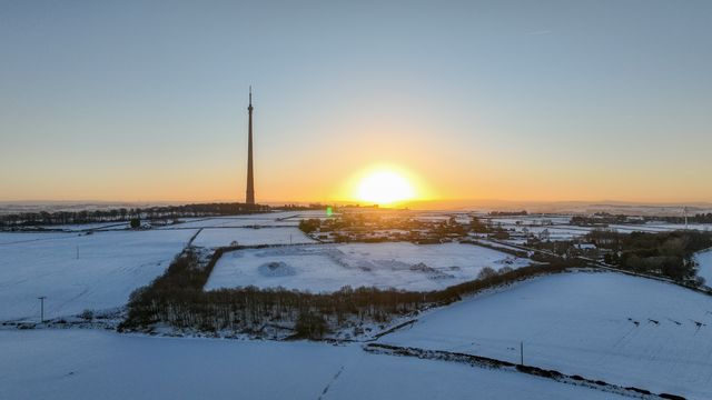 The sun sets over Emley Moor transmitting tower and the snow covered village of Emley as Sub-zero temperatures continue to hamper the north of the United Kingdom; Emley, Huddersfield, United Kingdom, 10th January 2025

(Photo by Mark Cosgrove/News Images)