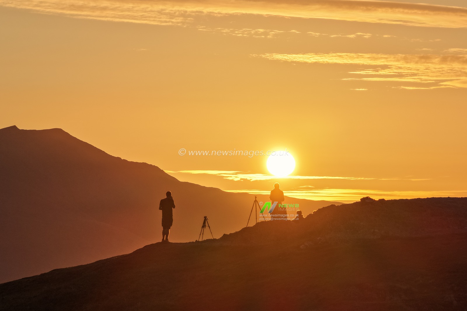 Photographers take pictures as the sun rises from the summit of Catbells overlooking Derwent Water and the town of Keswick In the Lake District, Cumbria, United Kingdom, 19th June 2025

(Photo by Mark Cosgrove/News Images)