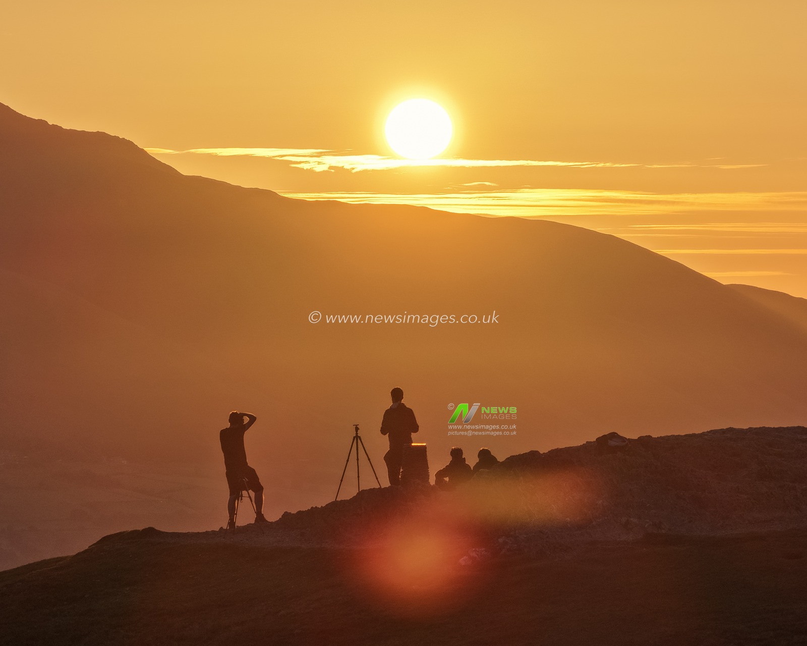 Photographers take pictures as the sun rises from the summit of Catbells overlooking Derwent Water and the town of Keswick In the Lake District, Cumbria, United Kingdom, 19th June 2025

(Photo by Mark Cosgrove/News Images)