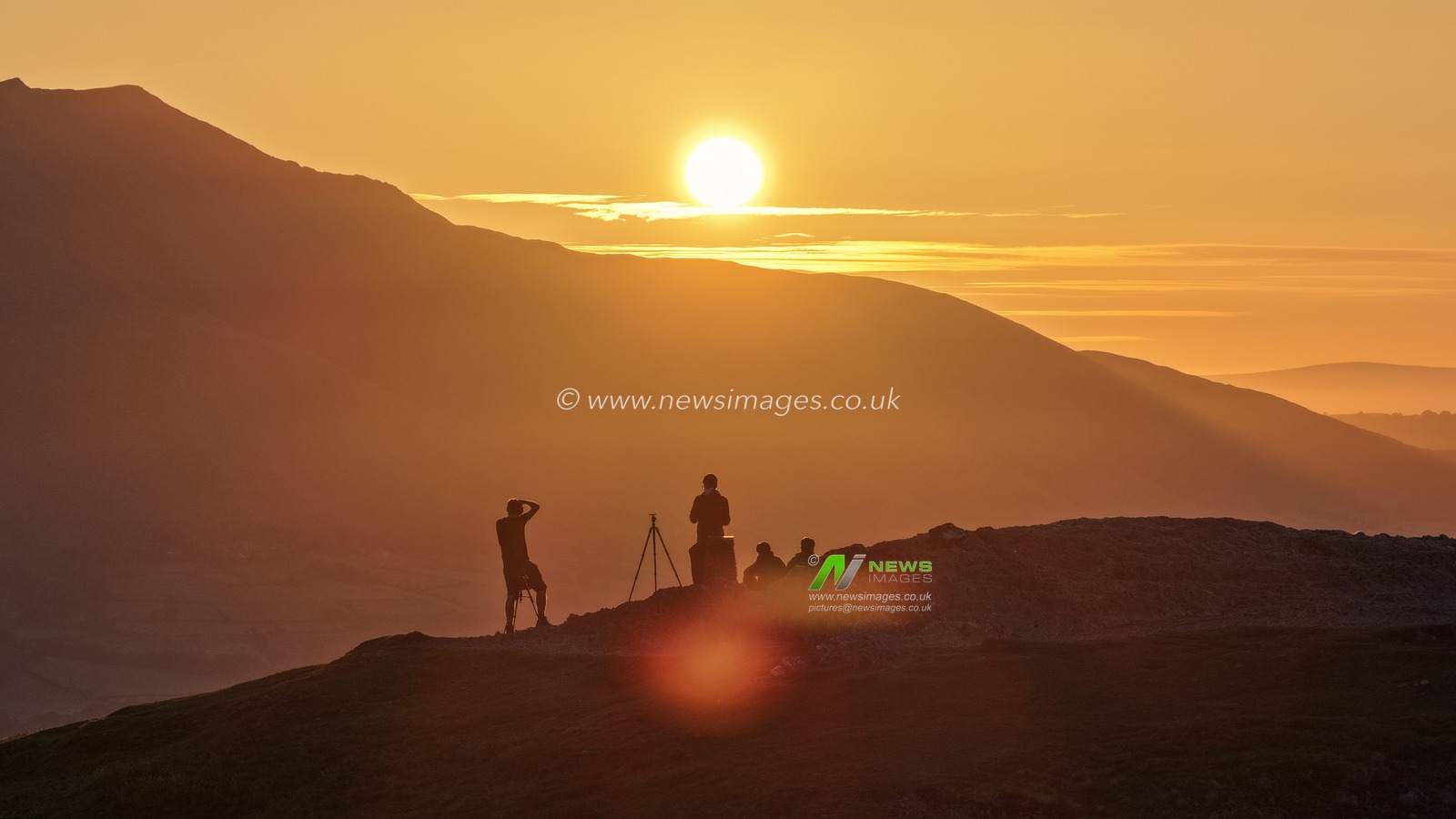 Photographers take pictures as the sun rises from the summit of Catbells overlooking Derwent Water and the town of Keswick In the Lake District, Cumbria, United Kingdom, 19th June 2025.

(Photo by Mark Cosgrove/News Images)