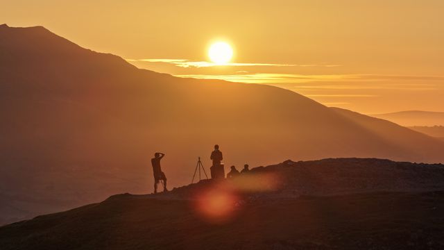 Photographers take pictures as the sun rises from the summit of Catbells overlooking Derwent Water and the town of Keswick In the Lake District, Cumbria, United Kingdom, 19th June 2025.

(Photo by Mark Cosgrove/News Images)