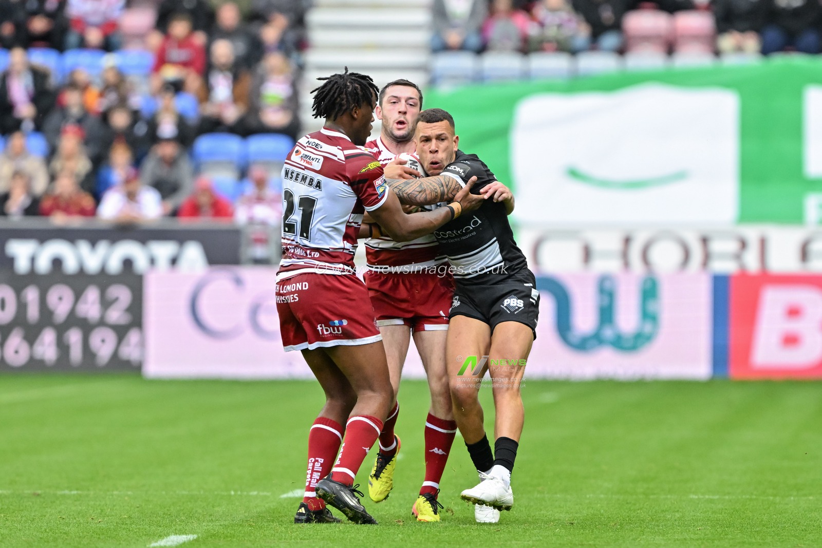 Carlos Tuimavave Hull FC is tackled by Junior Nsemba of Wigan Warriors and Jake Wardle of Wigan Warriors during the Betfred Super League Round 23 match Wigan Warriors vs Hull FC at DW Stadium, Wigan, United Kingdom, 25th August 2024

(Photo by Cody Froggatt/News Images)