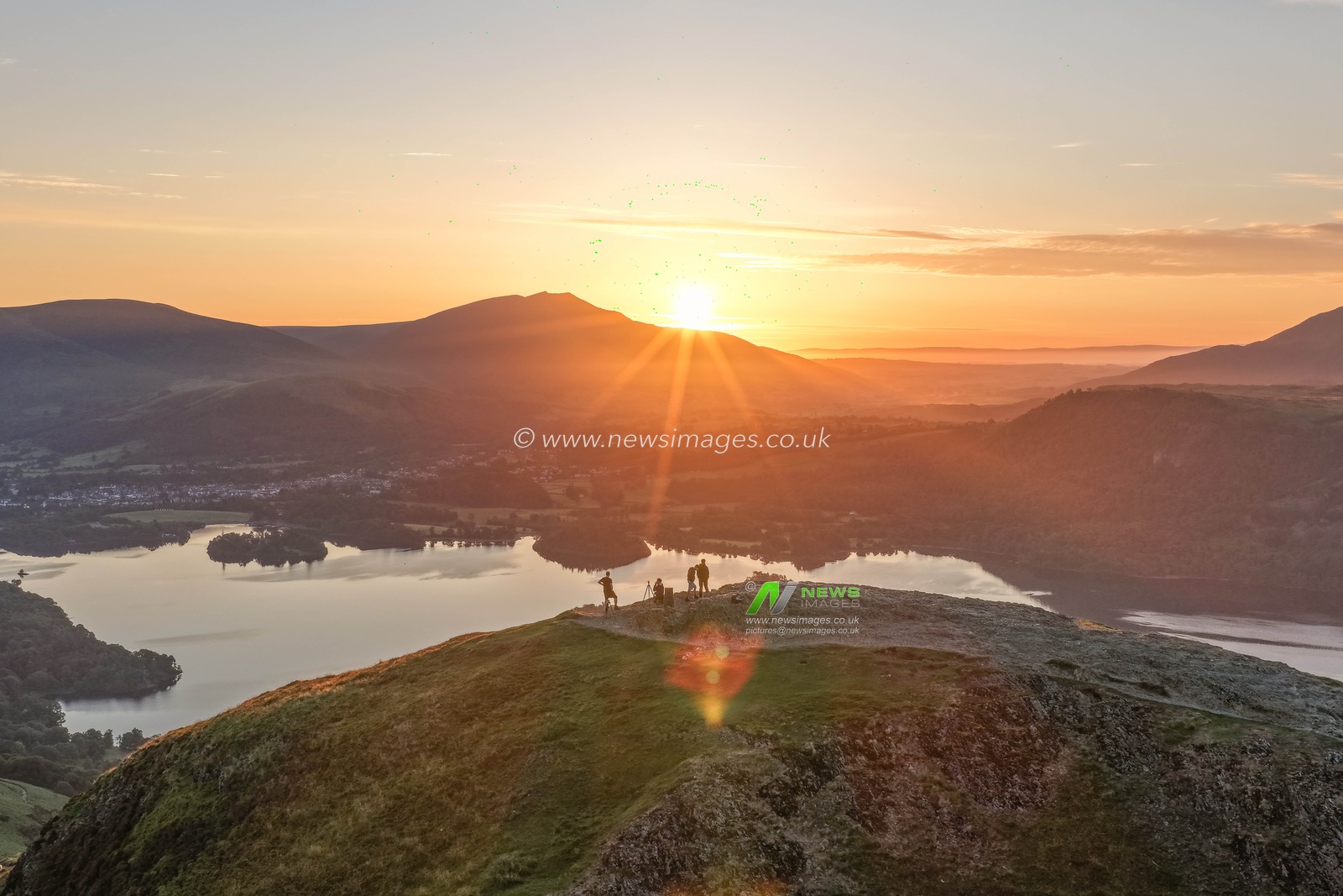 Photographers take pictures as the sun rises from the summit of Catbells overlooking Derwent Water and the town of Keswick In the Lake District, Cumbria, United Kingdom, 19th June 2025.

(Photo by Mark Cosgrove/News Images)