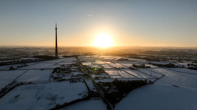 The sun sets over Emley Moor transmitting tower and the snow covered village of Emley as Sub-zero temperatures continue to hamper the north of the United Kingdom; Emley, Huddersfield, United Kingdom, 10th January 2025

(Photo by Mark Cosgrove/News Images)