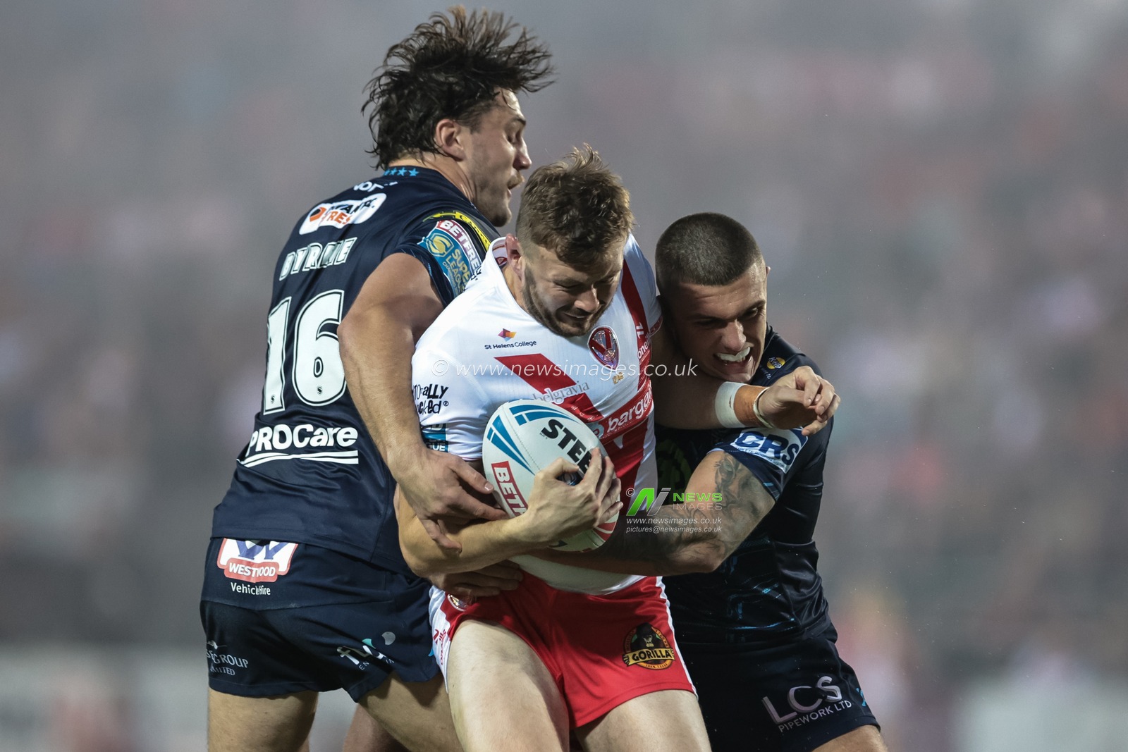 Joe Batchelor of St Helens is tackled by Brad O'neill of Wigan Warriors and Liam Byrne of Wigan Warriors during the Betfred Super League Round 25 match St Helens vs Wigan Warriors at Totally Wicked Stadium, St Helens, United Kingdom, 5th September 2025

(Photo by Mark Cosgrove/News Images)